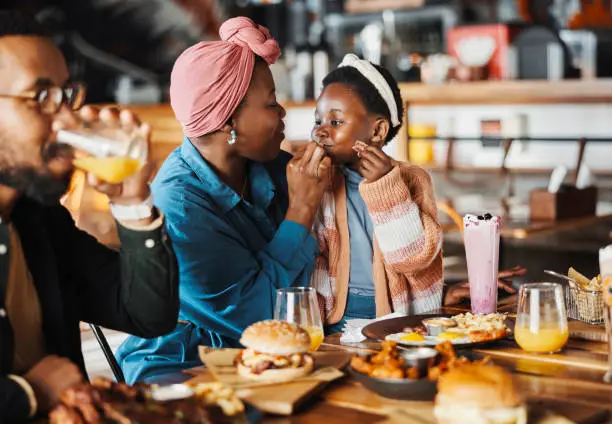 A loving family of four smiles and bonds over coffee and pastries at a cozy café table, highlighting warmth and connection.